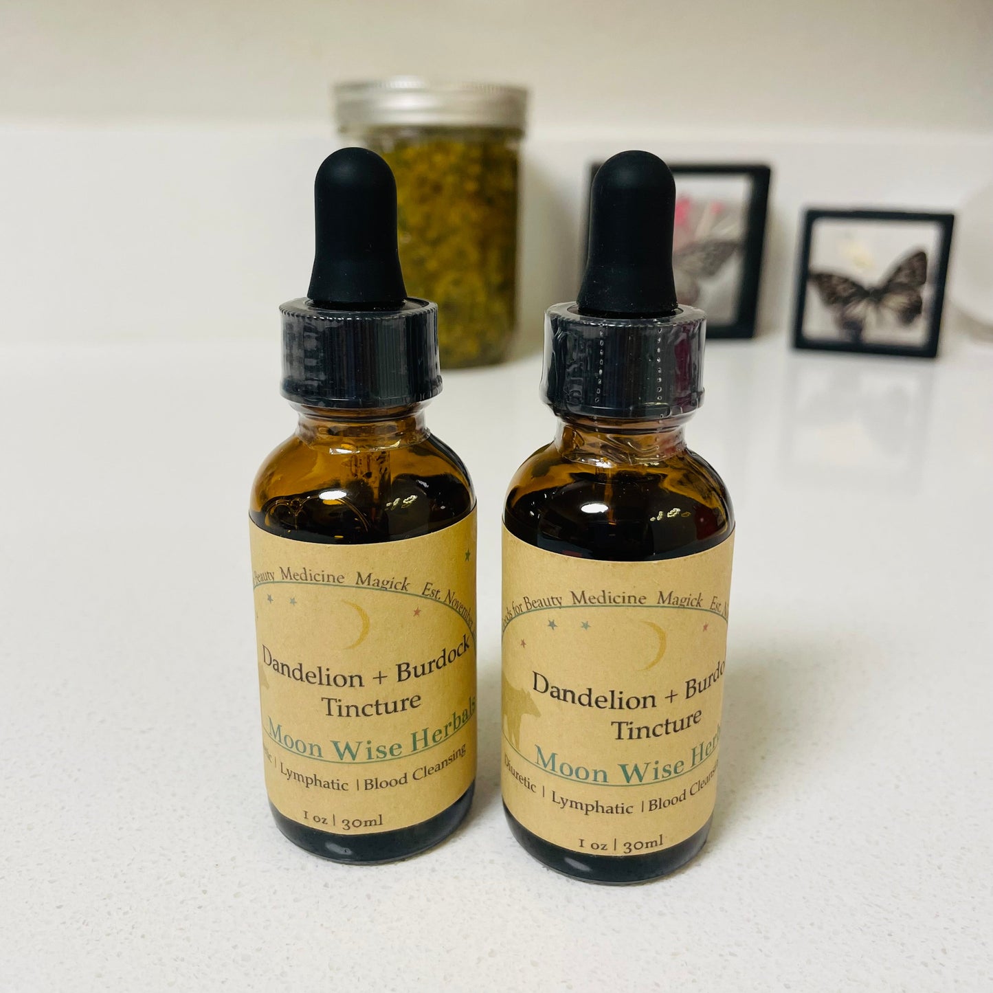 Two bottles of Dandelion + Burdock Tincture with droppers on a white surface.